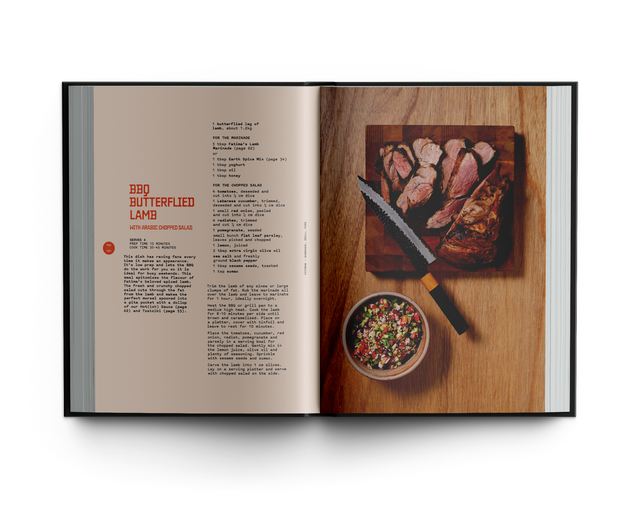 Open cookbook showing a recipe for roasted lamb with ingredients on a wooden board.